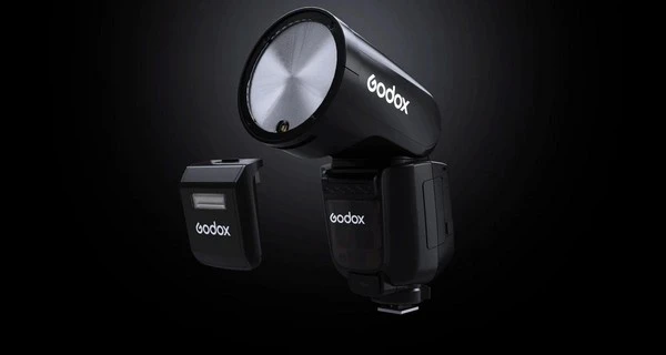 Спалах Godox V1Pro з круглою головкою на чорному студійному тлі та знімний модуль додаткового заповнюючого суб-спалаху SU-1 поруч